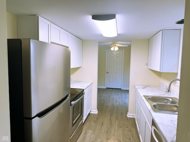 kitchen with light stone countertops, white cabinetry, sink, stainless steel appliances, and light hardwood / wood-style flooring