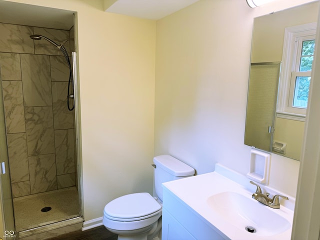 bathroom featuring a tile shower, vanity, and toilet