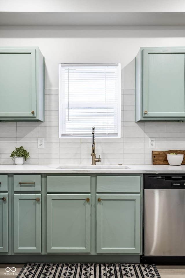 kitchen with decorative backsplash, stainless steel dishwasher, green cabinetry, and sink