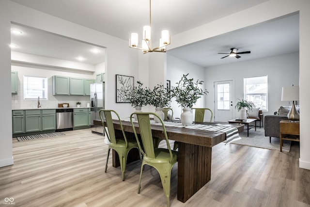 dining room featuring ceiling fan with notable chandelier, light hardwood / wood-style floors, and sink