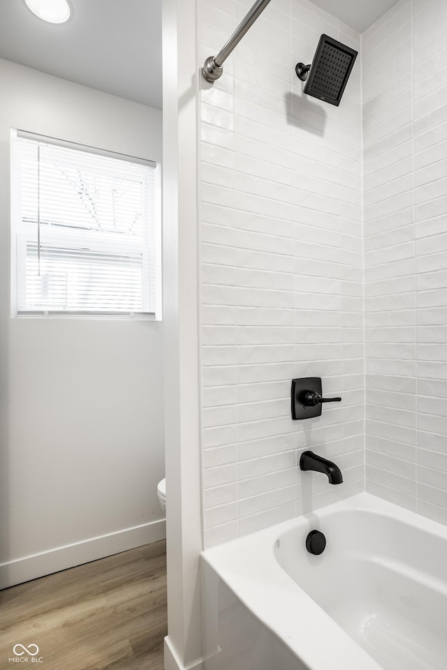 bathroom with hardwood / wood-style floors, shower / bath combination, and toilet