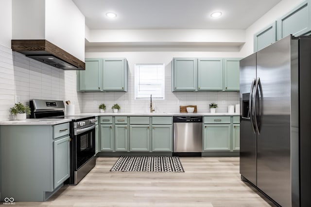 kitchen with custom exhaust hood, sink, decorative backsplash, appliances with stainless steel finishes, and light hardwood / wood-style floors