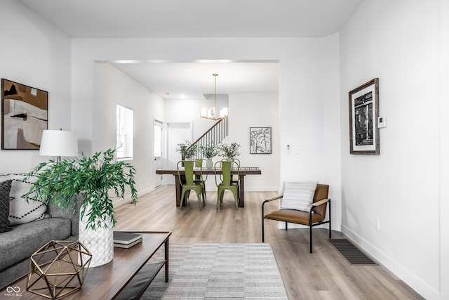 living room with light wood-type flooring and a notable chandelier