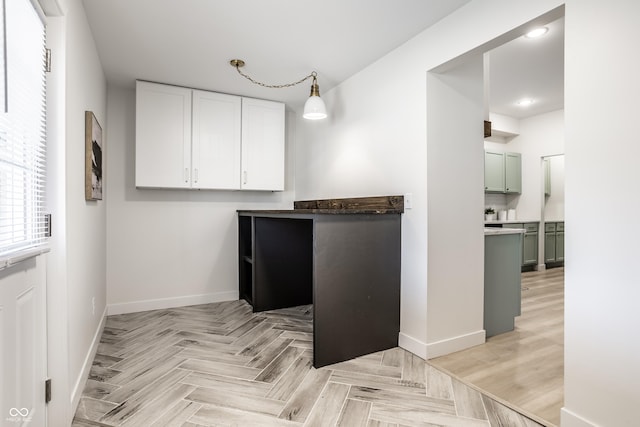 kitchen featuring white cabinets, light parquet floors, hanging light fixtures, and green cabinetry