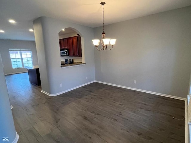 unfurnished dining area with dark hardwood / wood-style flooring and an inviting chandelier