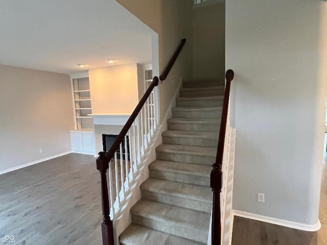 staircase with built in shelves and hardwood / wood-style flooring