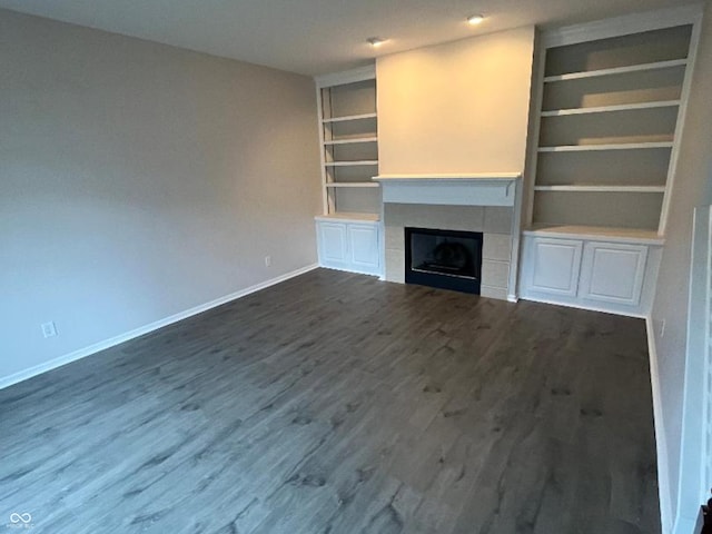 unfurnished living room with a fireplace, dark hardwood / wood-style flooring, and built in features