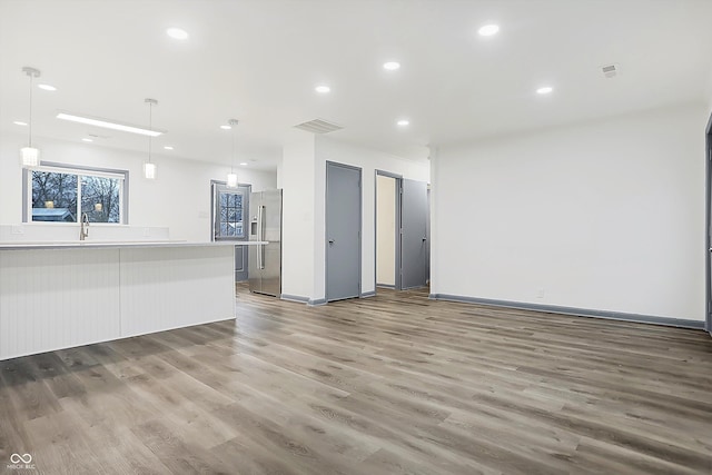 unfurnished living room with wood-type flooring and sink