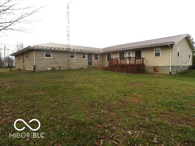 rear view of property featuring a lawn and a deck