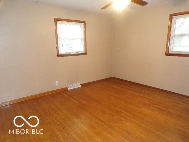 unfurnished room featuring wood-type flooring, a wealth of natural light, and ceiling fan