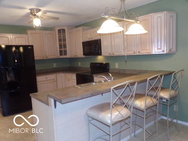 kitchen featuring black appliances, hanging light fixtures, ceiling fan, a kitchen bar, and kitchen peninsula