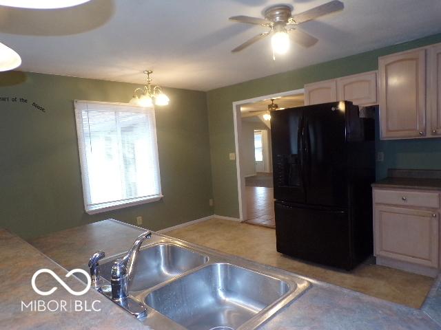 kitchen with sink, light brown cabinets, black fridge, a notable chandelier, and decorative light fixtures