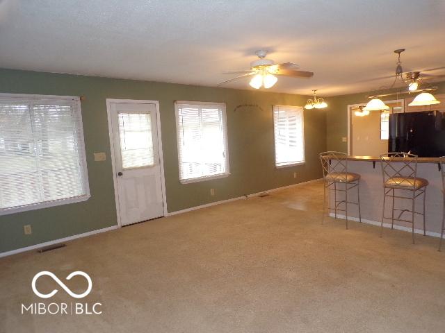 kitchen featuring a kitchen breakfast bar, light carpet, black refrigerator, and hanging light fixtures