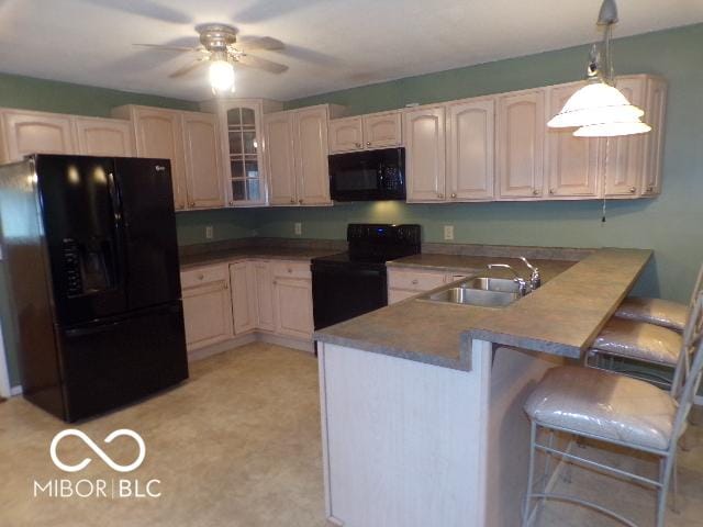 kitchen with kitchen peninsula, sink, black appliances, pendant lighting, and a breakfast bar area