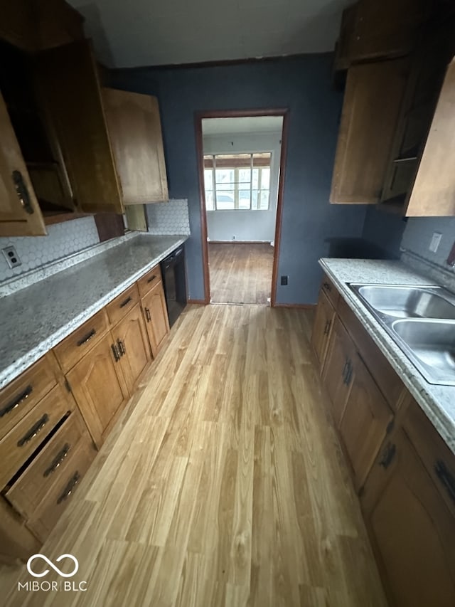 kitchen with black dishwasher, sink, and light hardwood / wood-style flooring