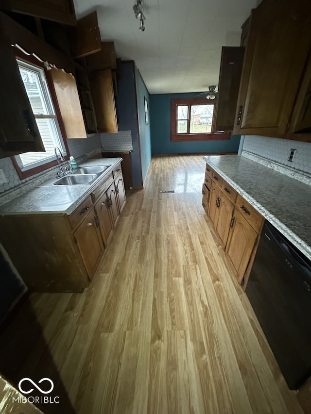 kitchen featuring dishwasher, rail lighting, sink, tasteful backsplash, and light wood-type flooring