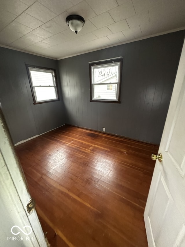 empty room featuring ornamental molding and dark wood-type flooring