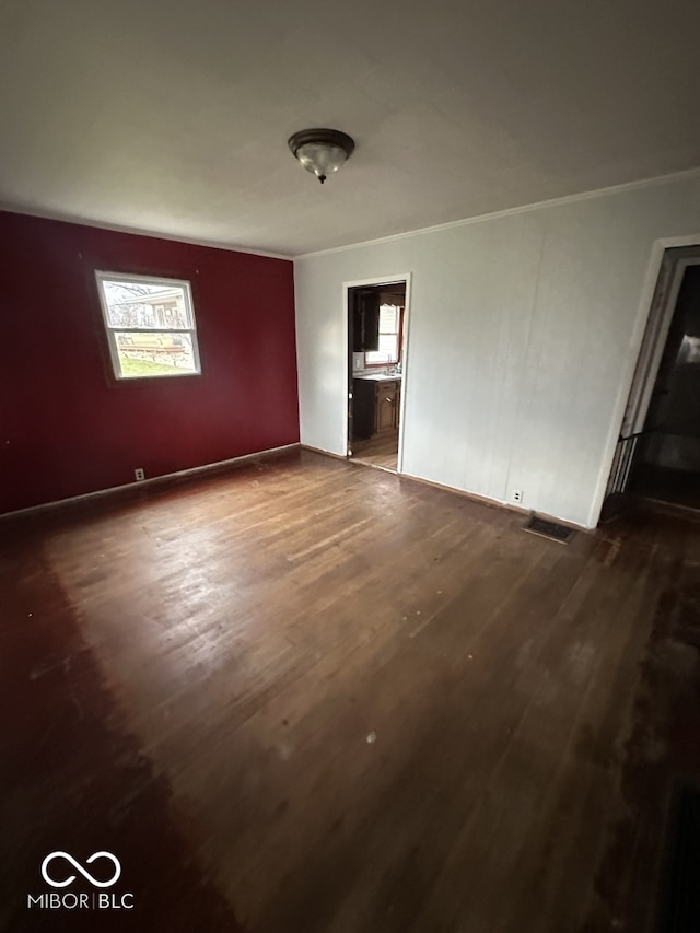 spare room featuring ornamental molding and dark wood-type flooring