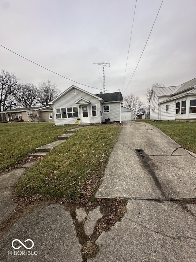 single story home featuring a garage, an outdoor structure, and a front lawn