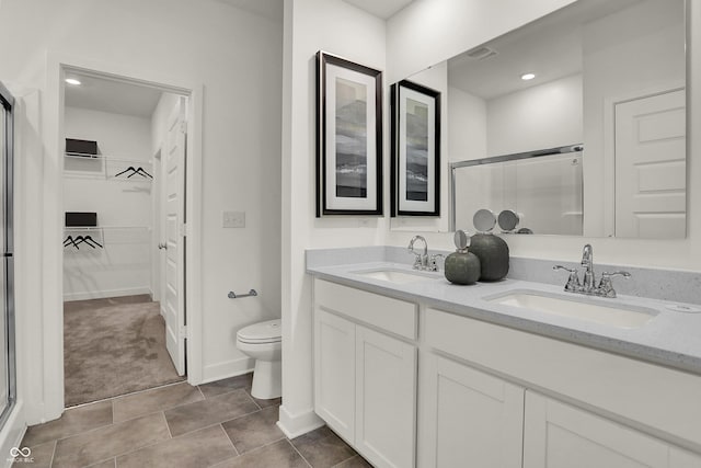 bathroom with tile patterned floors, vanity, toilet, and a shower with shower door