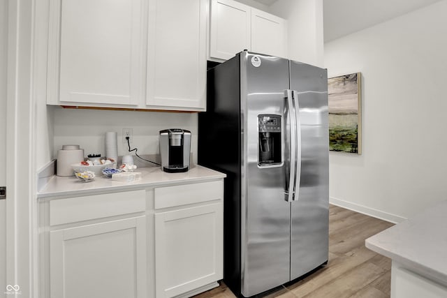 kitchen with stainless steel fridge, light wood-type flooring, and white cabinetry