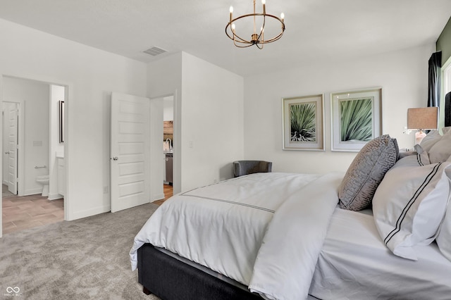 bedroom with a notable chandelier, light colored carpet, and ensuite bath