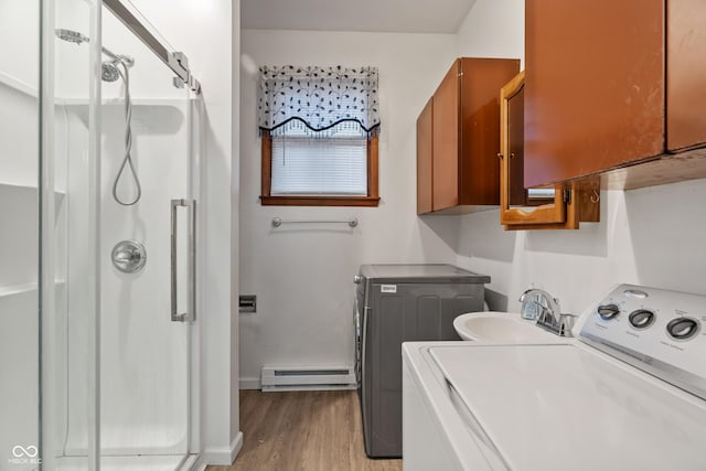 laundry room featuring sink, light hardwood / wood-style flooring, cabinets, washing machine and clothes dryer, and a baseboard radiator