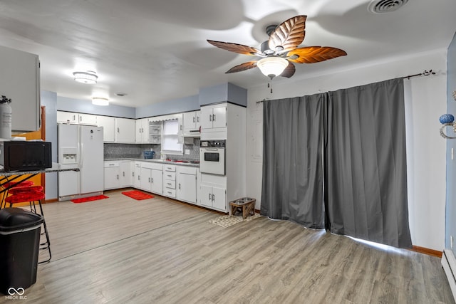 kitchen with white cabinetry, decorative backsplash, white appliances, and light hardwood / wood-style flooring