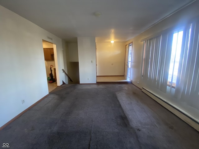 carpeted empty room featuring a baseboard heating unit