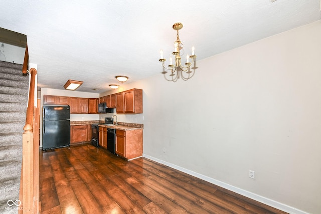 kitchen with sink, dark wood-type flooring, a notable chandelier, decorative light fixtures, and black appliances