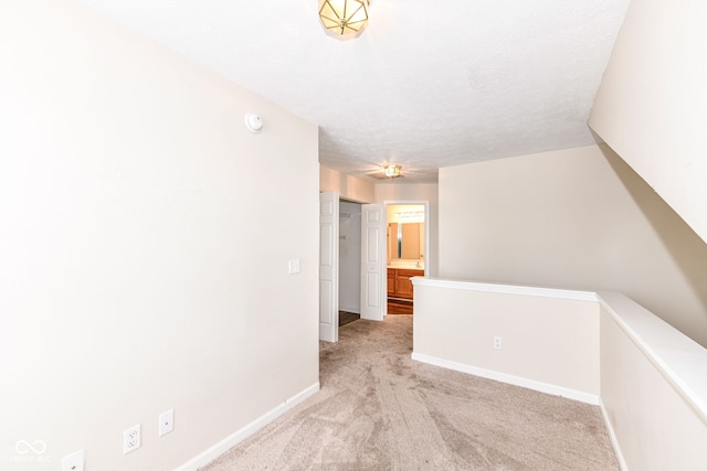 corridor featuring a textured ceiling and light carpet