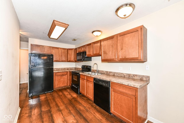 kitchen with black appliances, dark hardwood / wood-style floors, sink, and a textured ceiling