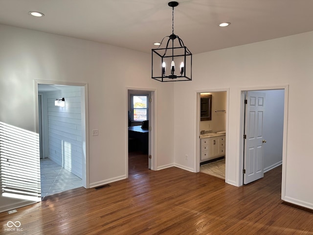 unfurnished dining area featuring dark hardwood / wood-style flooring, an inviting chandelier, and sink