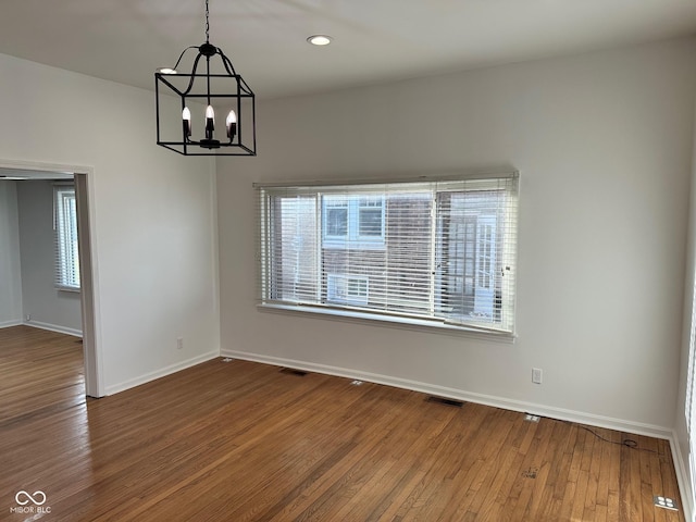 empty room featuring hardwood / wood-style flooring and an inviting chandelier