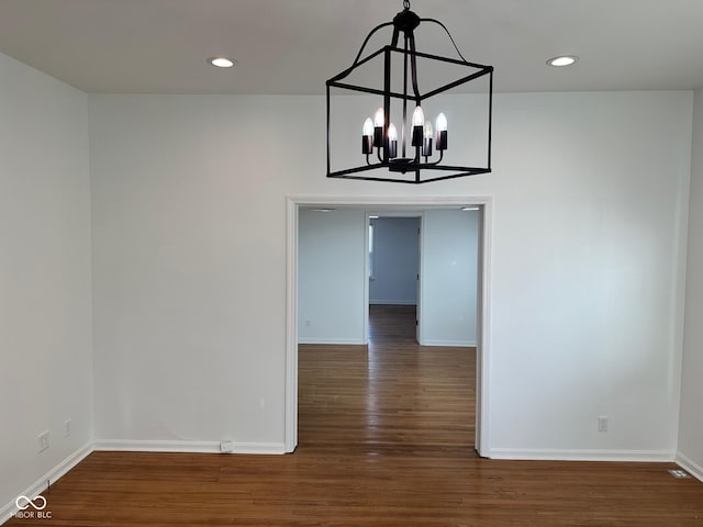 unfurnished dining area featuring a chandelier and dark wood-type flooring