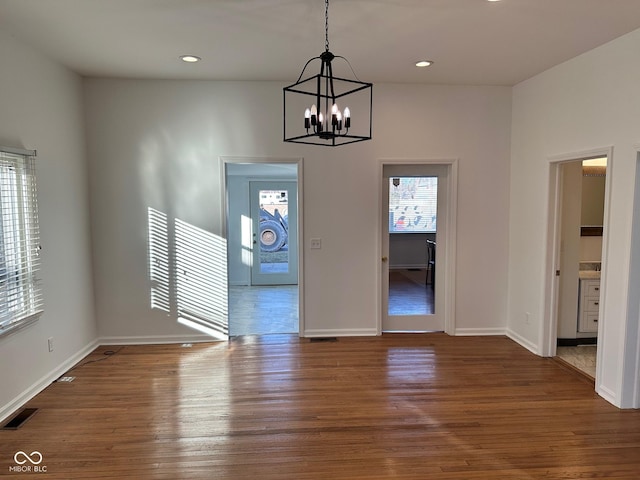 unfurnished dining area featuring a notable chandelier and dark wood-type flooring