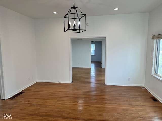 unfurnished dining area featuring dark hardwood / wood-style floors and an inviting chandelier