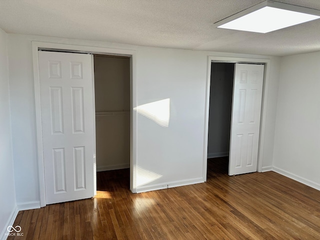 unfurnished bedroom with a textured ceiling and dark wood-type flooring