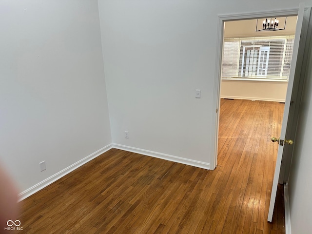 unfurnished room featuring wood-type flooring and a chandelier