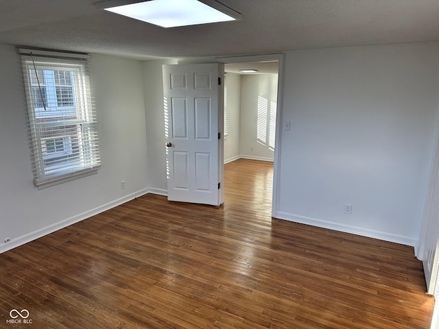 spare room featuring a textured ceiling and dark hardwood / wood-style flooring