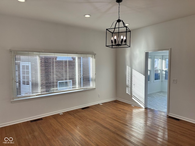 unfurnished dining area featuring a chandelier, wood-type flooring, and plenty of natural light