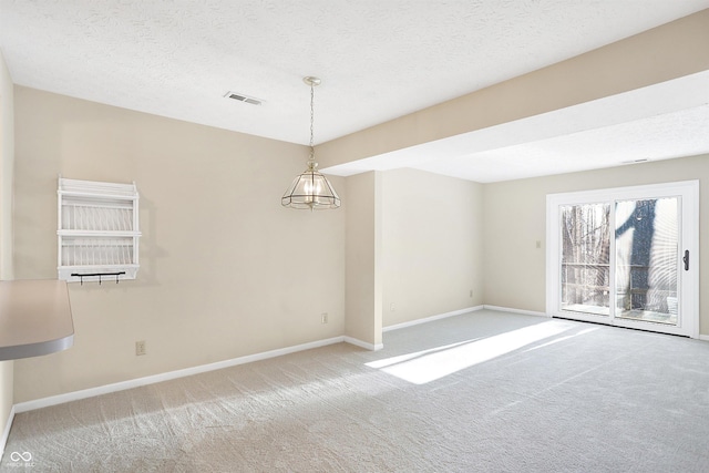 empty room featuring carpet, a textured ceiling, and a notable chandelier