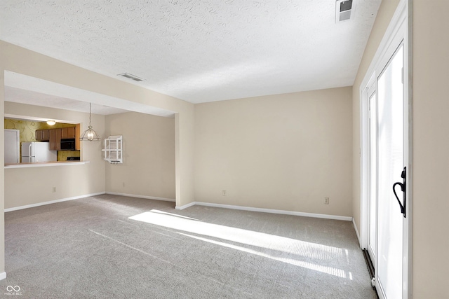 unfurnished room with carpet, a textured ceiling, and an inviting chandelier