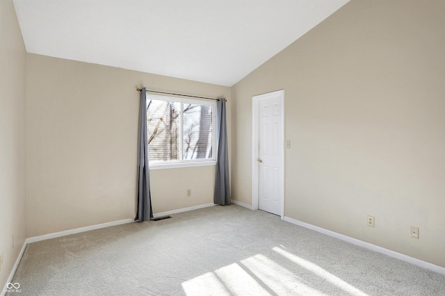 spare room with light colored carpet and lofted ceiling