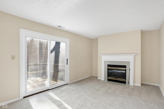 unfurnished living room with light carpet, a textured ceiling, and a fireplace