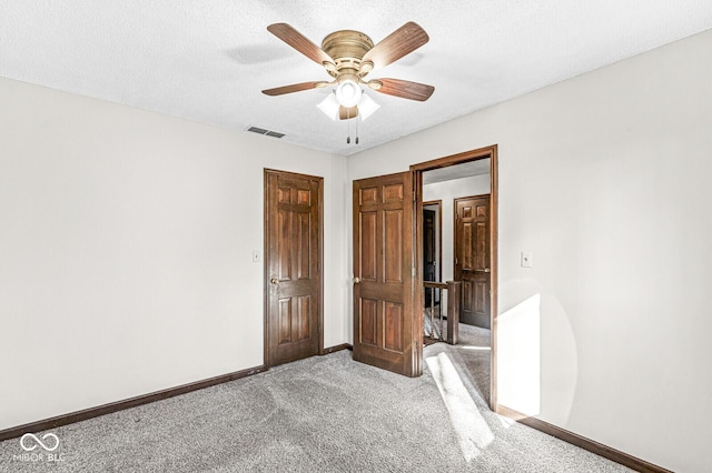 unfurnished bedroom with carpet, a textured ceiling, and ceiling fan