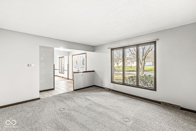 empty room with a textured ceiling and light colored carpet