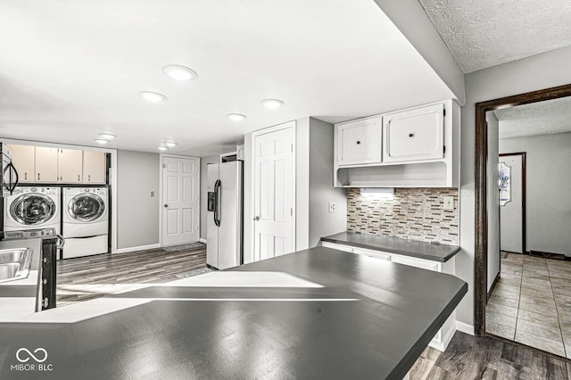 kitchen with white cabinetry, tasteful backsplash, washing machine and dryer, dark hardwood / wood-style floors, and stainless steel fridge