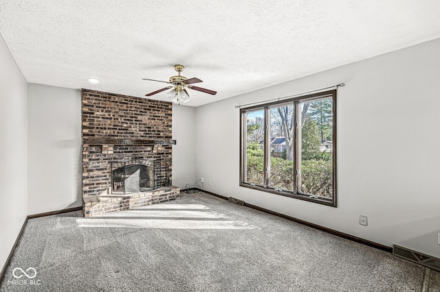 unfurnished living room featuring carpet flooring, ceiling fan, a fireplace, and a textured ceiling