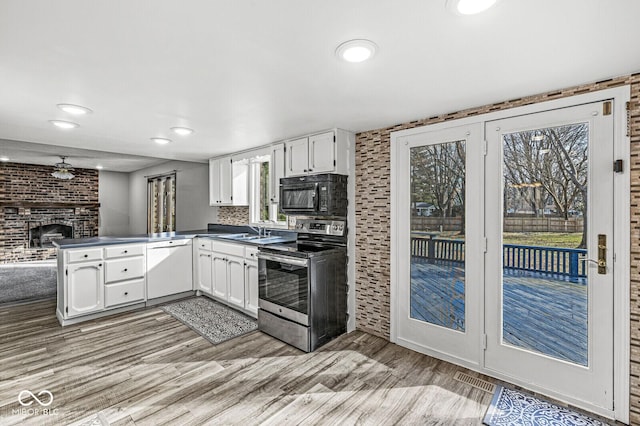 kitchen featuring white cabinetry, backsplash, white dishwasher, a fireplace, and stainless steel range with electric cooktop